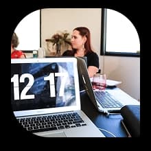 Open laptop on a meeting table with people in discussion